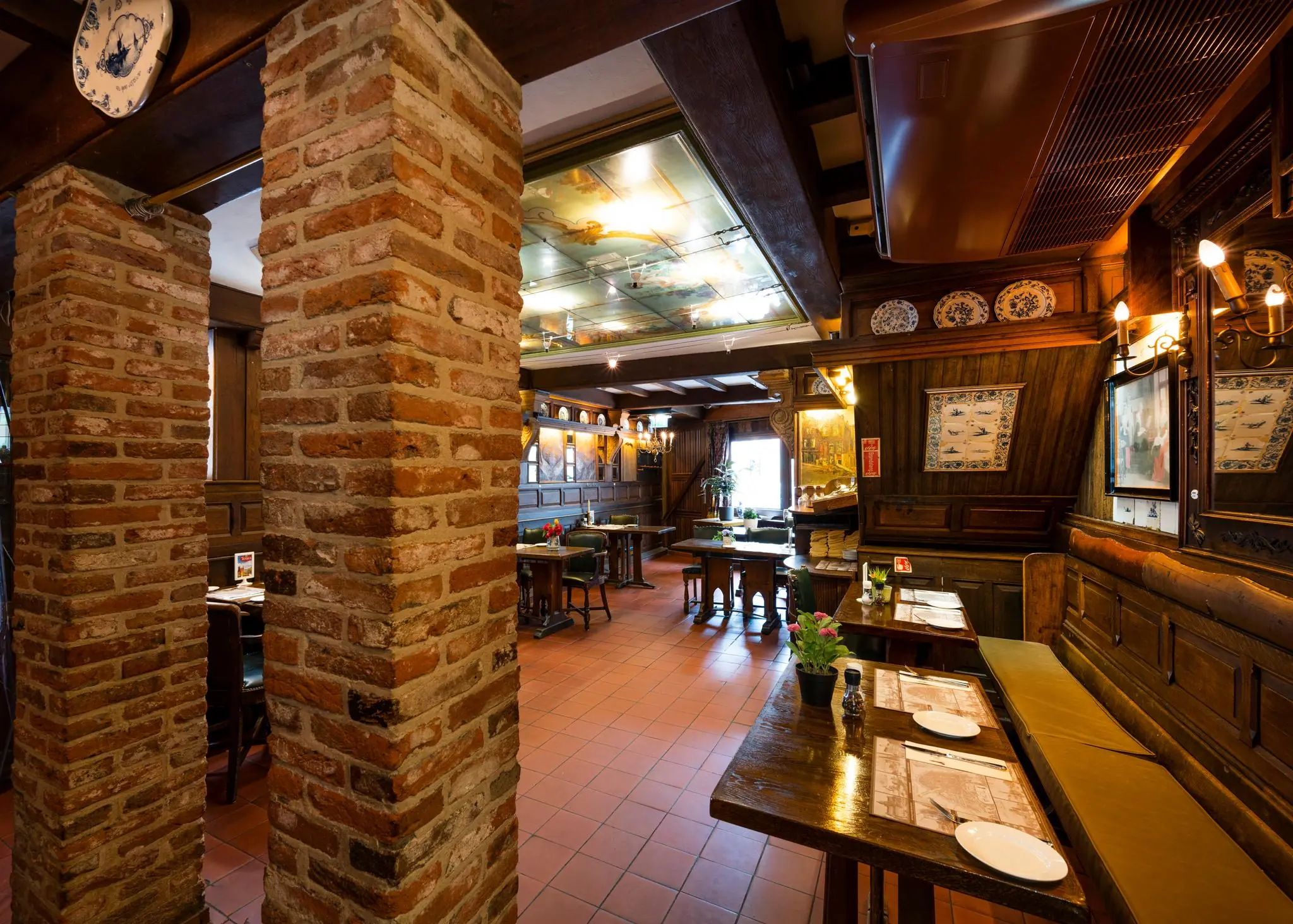 Gezellige, klassiek ingerichte eetruimte met houten meubilair en bakstenen pilaren aan de Nieuwezijds Voorburgwal.